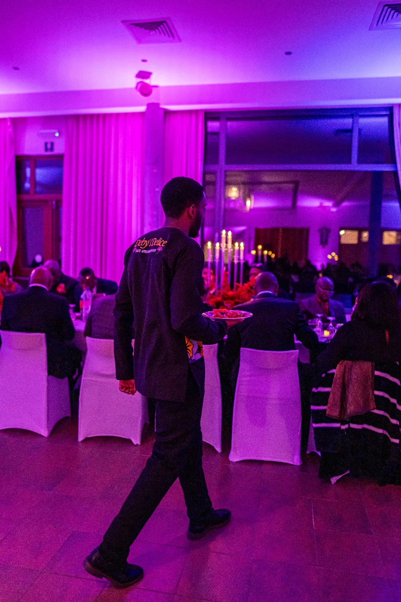 Een teamlid van Deby’s Delice tijdens een paars verlichte receptie.