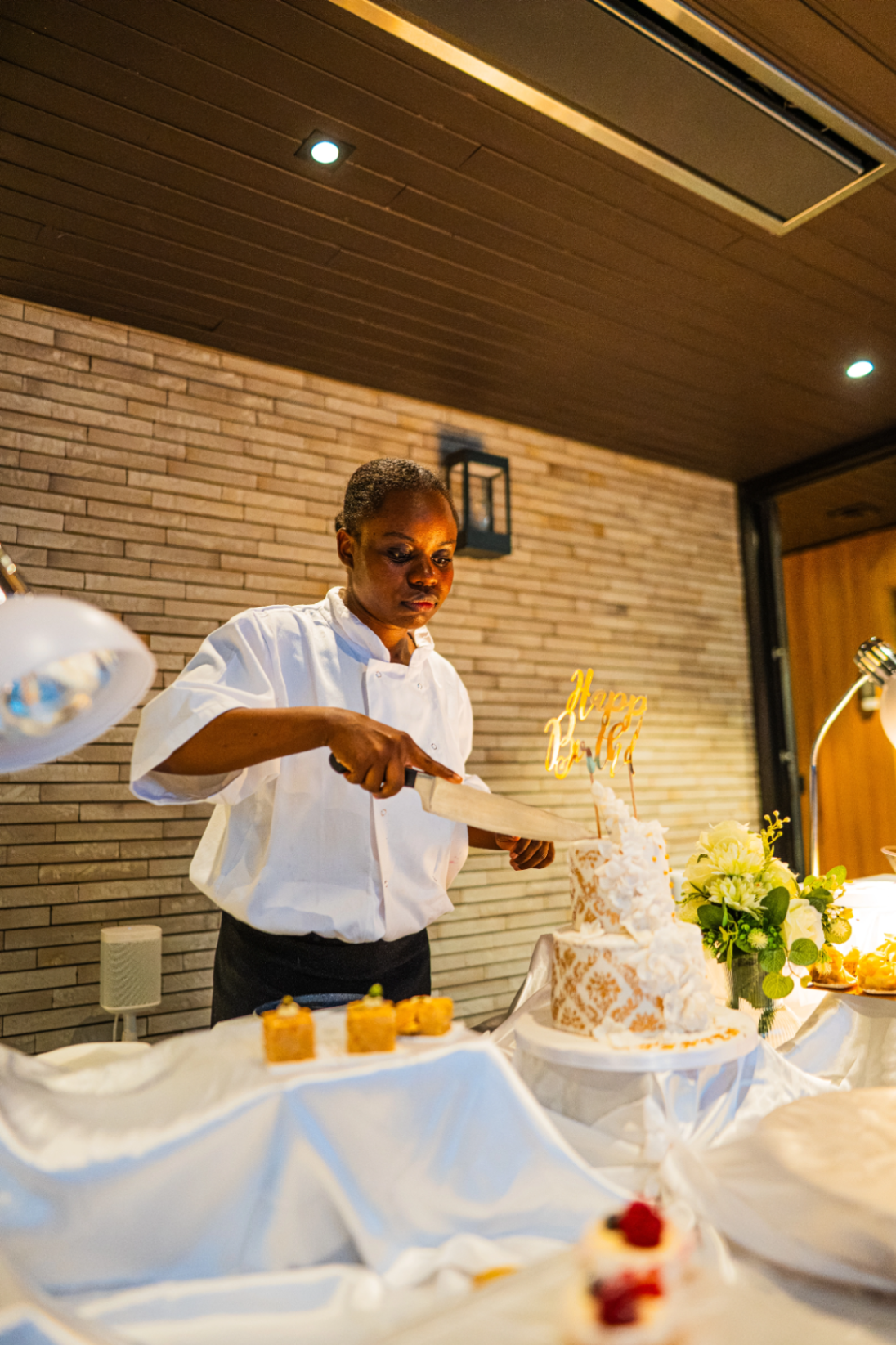 La Cheffe Deby's Delice découpant un gâteau de célébration
