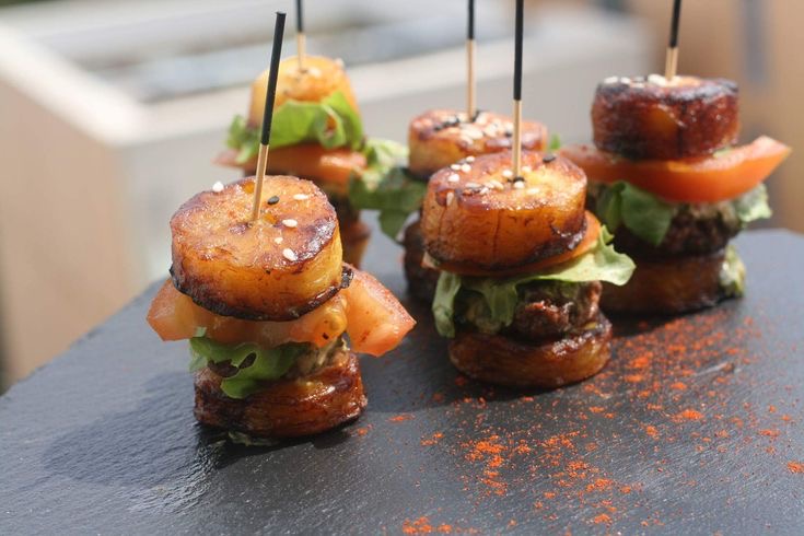 Mini burgers de plantain caramélisé garnis de bœuf, salade et tomate, présentés sur ardoise — création signature Deby's Delice