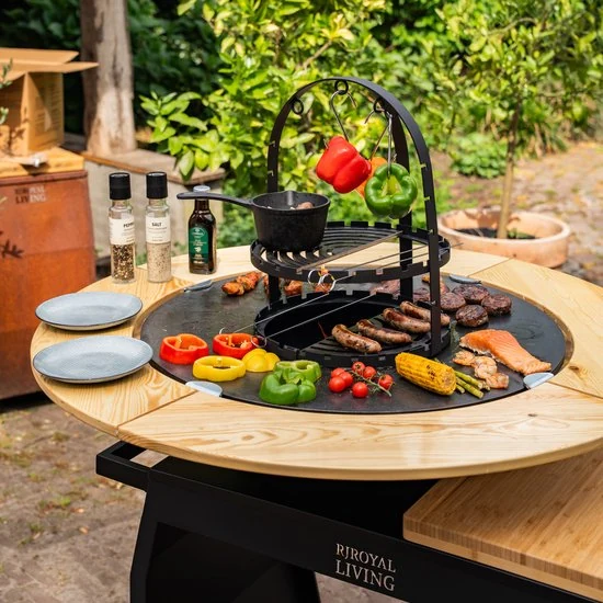 Grillades et légumes sur une plaque de cuisson circulaire en extérieur.